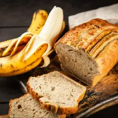 Pyszne, wilgotne ciasto bananowe, które zawsze się udaje. Obok leżą dojrzałe banany, gotowe do pieczenia.