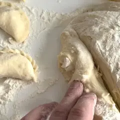 Ręce formują ciasto na pierogi. Wkrótce dowiesz się, ile gotować pierogi, by były idealne.