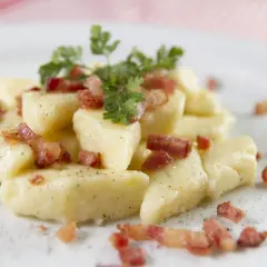 Kopytka z chrupiącym boczkiem i natką pietruszki, posypane pieprzem. Pyszne danie, które aż prosi się, by je zjeść.