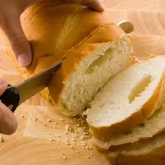 Ręce kroją świeżo upieczony chleb na desce. Idealny przepis na chleb, który zachwyci każdego.