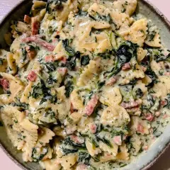 Makaron farfalle w kremowym sosie szpinakowym z kawałkami boczku. Pyszne danie, które zachwyci każdego.