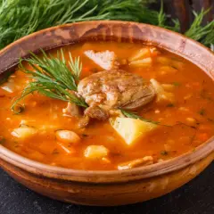 Gęsta, aromatyczna zupa ogonowa z kawałkami mięsa i ziemniaków, udekorowana świeżym koperkiem.
