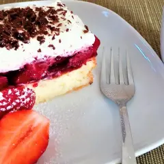 Pyszny biszkopt z galaretką i kremem mascarpone, udekorowany startą czekoladą i świeżymi truskawkami. Idealny deser.