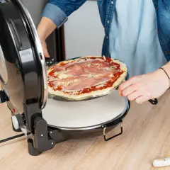 Osoba wkłada do pieca pizzę z szynką. Już niedługo będzie można ją zjeść!
