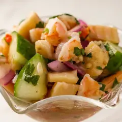 Orzeźwiające ceviche z krewetkami, ogórkiem, czerwoną cebulą i kolendrą w szklanej miseczce.