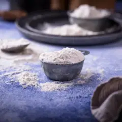 Mąka w miarkach i na stole, obok ściereczka.