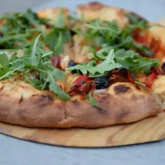 Pyszna pizza z rukolą i oliwkami, idealna na podstawie z przepisu na ciasto do pizzy.
