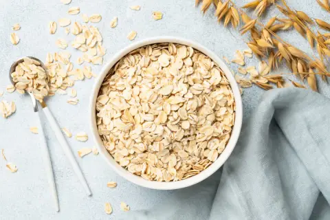 Misternie ułożone płatki owsiane w misce i na łyżce. Czy płatki owsiane mają gluten? Zwykłe płatki owsiane zawierają gluten, chyba że są certyfikowane jako bezglutenowe.