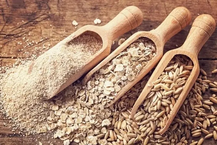 Trzy drewniane łopatki z owsem: mąka, płatki i ziarna. Idealne dla osób unikających glutenu.