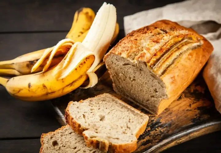 Pyszne, wilgotne ciasto bananowe, które zawsze się udaje. Obok leżą dojrzałe banany, gotowe do pieczenia.