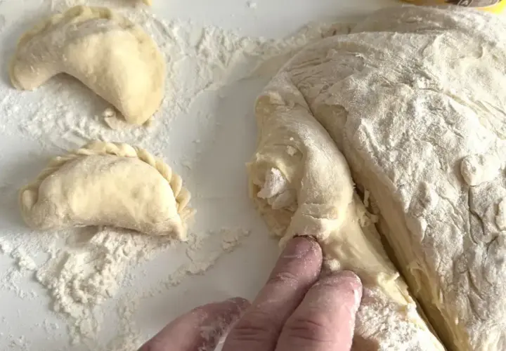 Ręce formują ciasto na pierogi. Wkrótce dowiesz się, ile gotować pierogi, by były idealne.