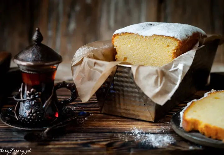 Puszysta babka włoska, oprószona cukrem pudrem, czeka na degustację obok aromatycznej herbaty w orientalnej filiżance.