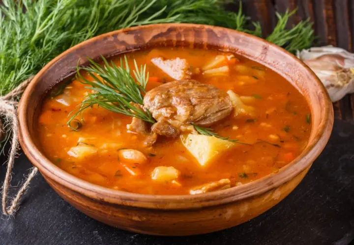 Gęsta, aromatyczna zupa ogonowa z kawałkami mięsa i ziemniaków, udekorowana świeżym koperkiem.