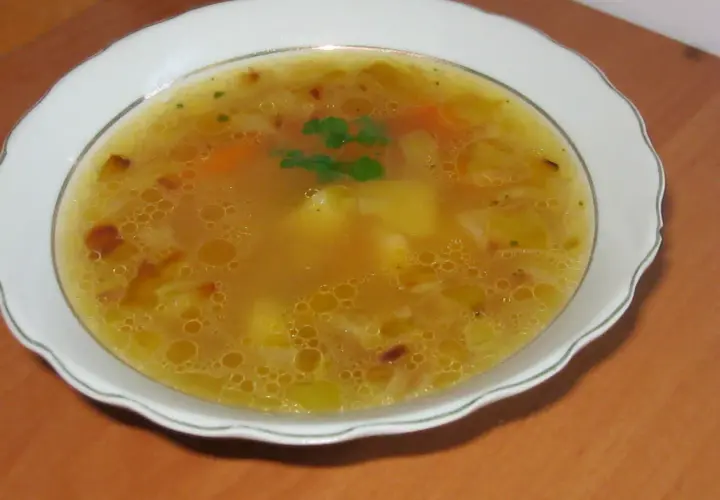 Prosta zupa cebulowa z ziemniakami, z dodatkiem marchewki i ziół, podana w białej misce.