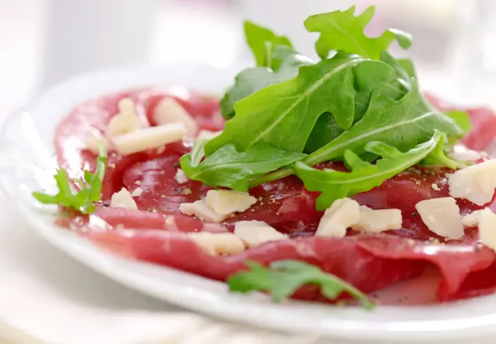 Cienkie plastry wołowiny z rukolą i parmezanem, skropione pysznym sosem do carpaccio.