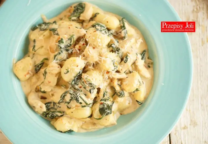 Pyszne gnocchi z kurczakiem i szpinakiem w kremowym sosie, posypane parmezanem. Idealne danie na szybki obiad.
