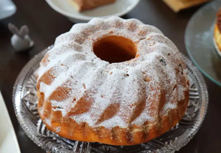 Puszysta babka drożdżowa, jak z babcinego przepisu, oprószona cukrem pudrem, na kryształowej paterze.