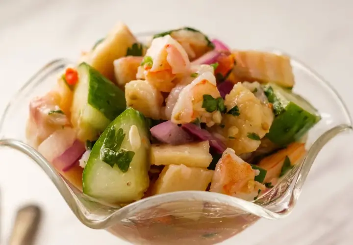 Orzeźwiające ceviche z krewetkami, ogórkiem, czerwoną cebulą i kolendrą w szklanej miseczce.