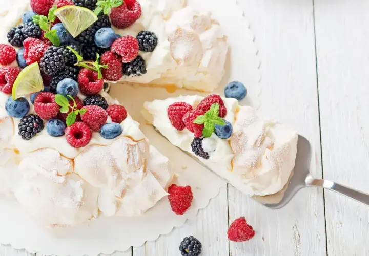 Beza pavlova która zawsze wychodzi, udekorowana świeżymi malinami, borówkami, jeżynami i plasterkami limonki.