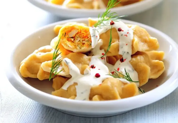 Pyszne pierogi z farszem, polane śmietaną i posypane koperkiem i pieprzem. Idealny obiad na sobotę.