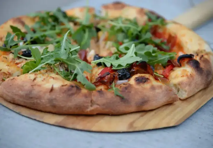 Pyszna pizza z rukolą i oliwkami, idealna na podstawie z przepisu na ciasto do pizzy.