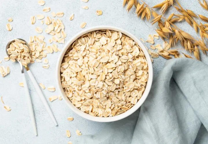 Misternie ułożone płatki owsiane w misce i na łyżce. Czy płatki owsiane mają gluten? Zwykłe płatki owsiane zawierają gluten, chyba że są certyfikowane jako bezglutenowe.