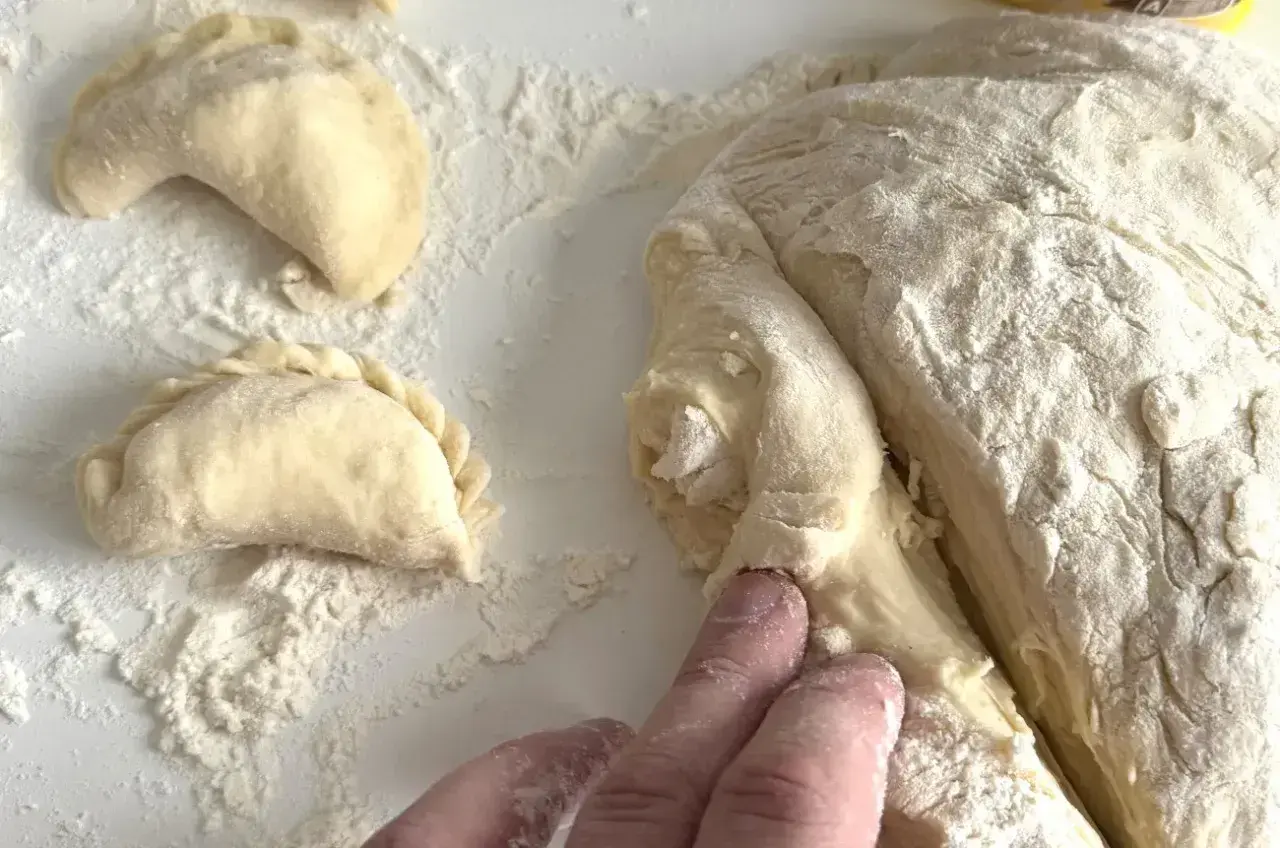 Ręce formują ciasto na pierogi. Wkrótce dowiesz się, ile gotować pierogi, by były idealne.