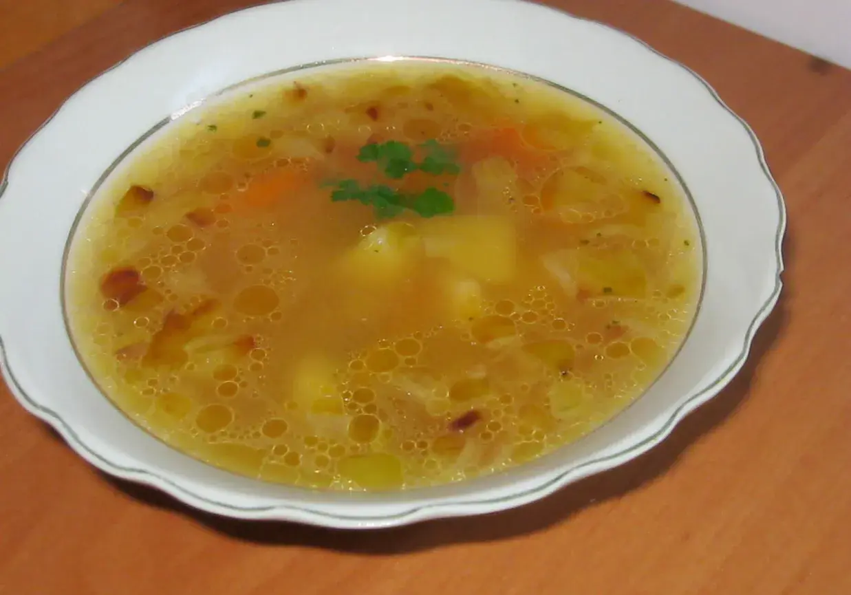 Prosta zupa cebulowa z ziemniakami, z dodatkiem marchewki i ziół, podana w białej misce.