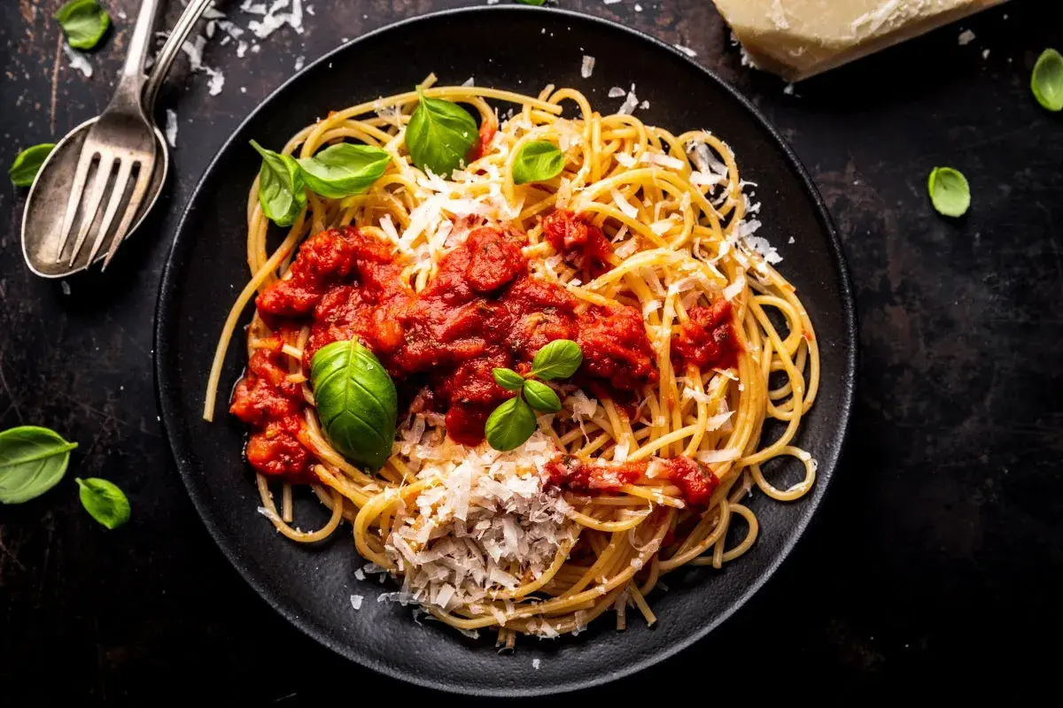 Pyszne spaghetti z sosem pomidorowym, parmezanem i bazylią. Idealny przepis na sos do spaghetti, który zachwyci każdego.