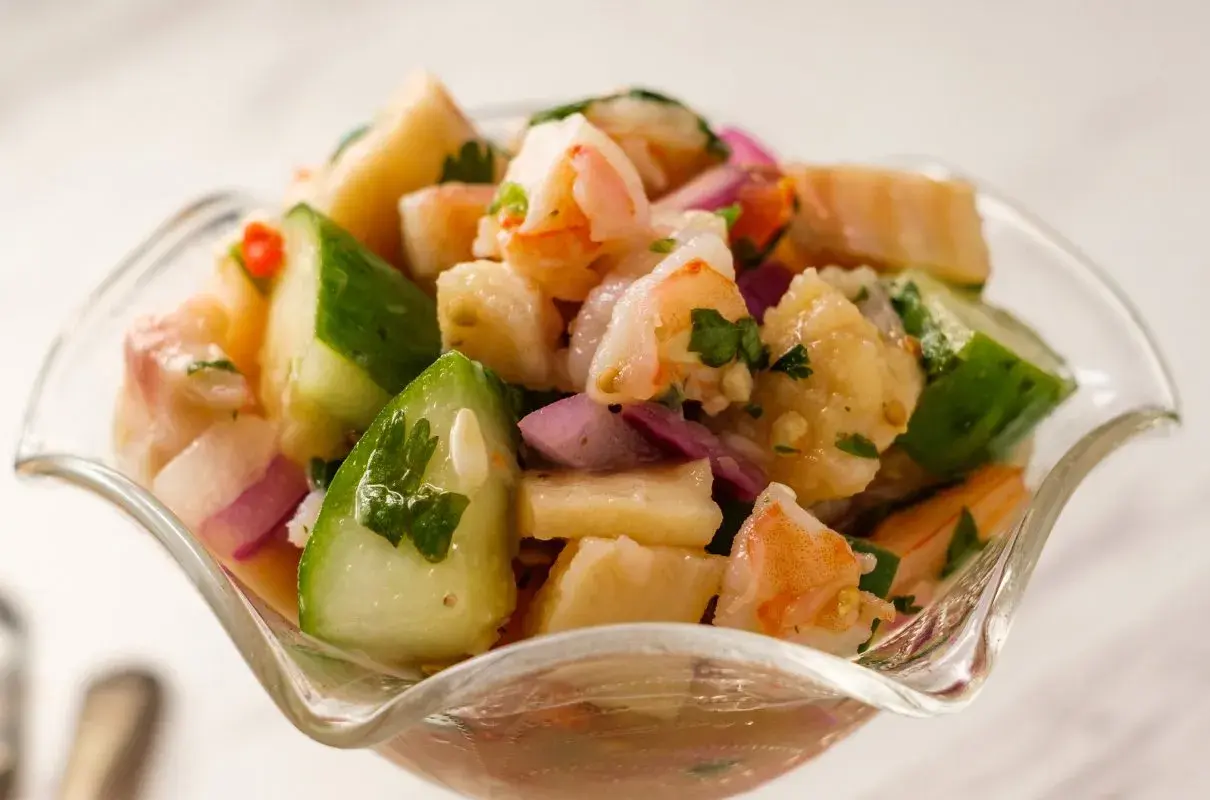 Orzeźwiające ceviche z krewetkami, ogórkiem, czerwoną cebulą i kolendrą w szklanej miseczce.