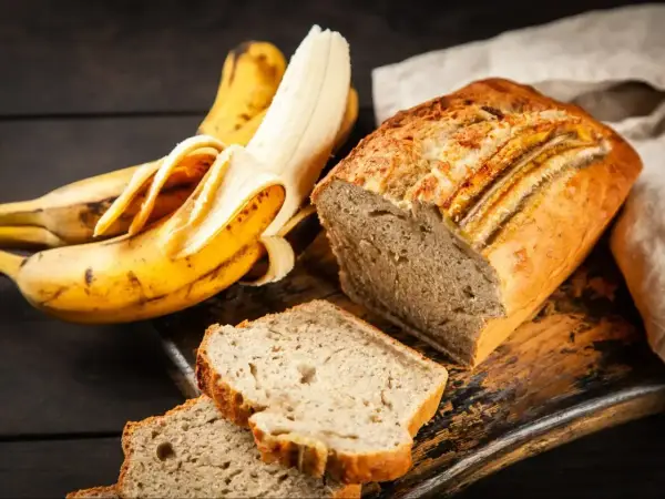 Pyszne, wilgotne ciasto bananowe, które zawsze się udaje. Obok leżą dojrzałe banany, gotowe do pieczenia.