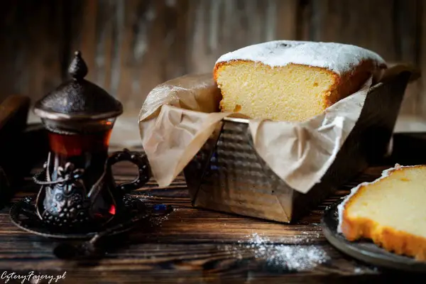 Puszysta babka włoska, oprószona cukrem pudrem, czeka na degustację obok aromatycznej herbaty w orientalnej filiżance.