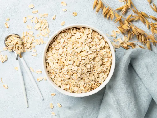 Misternie ułożone płatki owsiane w misce i na łyżce. Czy płatki owsiane mają gluten? Zwykłe płatki owsiane zawierają gluten, chyba że są certyfikowane jako bezglutenowe.